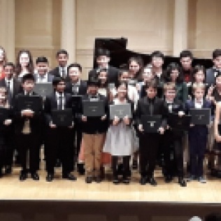 Foto di gruppo dei giovani musicisti sul palco del Carnegie Hall